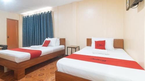 ダバオシティにあるRedDoorz at Casa Buena Dormitel Davao Cityのベッド2台(赤と白のシーツ付)が備わる客室です。