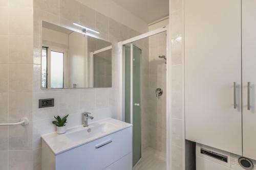 une salle de bain blanche avec un lavabo et un miroir dans l'établissement New T2 proche Monaco, centre ville, magnifique terasse, à Roquebrune-Cap-Martin
