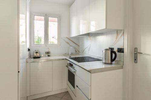une cuisine blanche avec des armoires blanches et une fenêtre dans l'établissement New T2 proche Monaco, centre ville, magnifique terasse, à Roquebrune-Cap-Martin