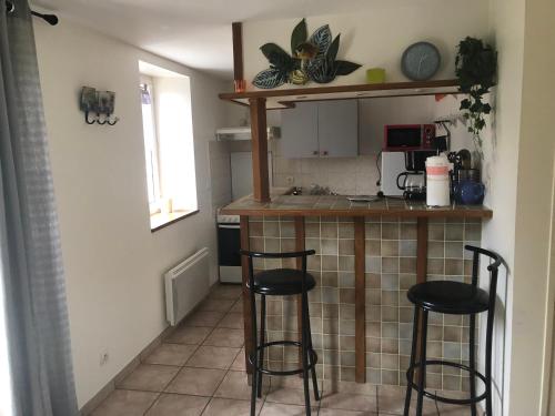 a kitchen with two bar stools and a counter at Normandia Parfum de pommes et d'histoire in Nonant
