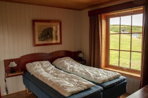 a bed in a bedroom with a window at Rondane Haukliseter Fjellhotell in Høvringen