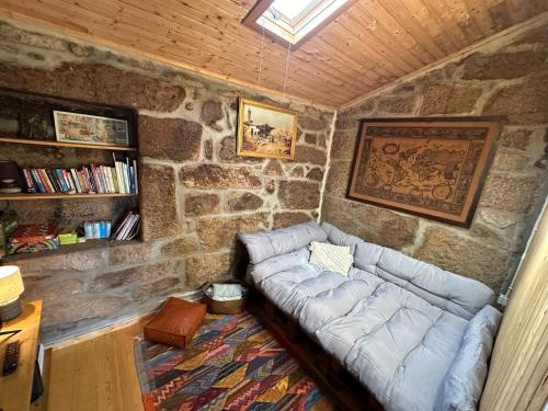 uma sala de estar com um sofá numa parede de pedra em Casa da Eira 
