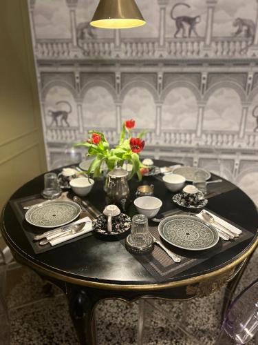 a table with plates and a vase of flowers on it at B&B Colombo by Addler House Ospitality in Mestre