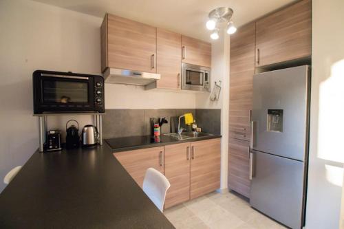 Il comprend une cuisine équipée d'un comptoir noir et d'un réfrigérateur. dans l'établissement Charmant studio en centre-ville proche Monaco, à Cap d'Ail