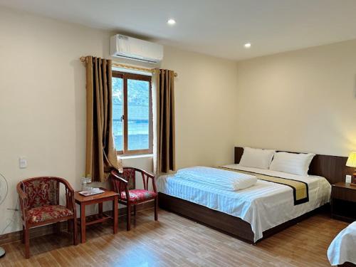 1 dormitorio con 1 cama, 2 sillas y ventana en Sơn Nguyên 2, en Hà Tây