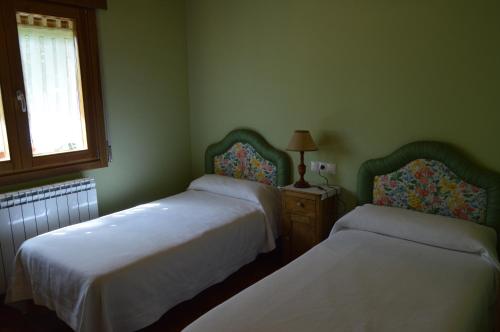 Cette chambre comprend deux lits et une table avec une lampe. dans l'établissement La Casa del Rio - La Lobera Casa Rural, à Molinos de Razón