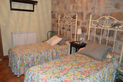 een slaapkamer met 2 bedden en een stenen muur bij La Casa del Rio - La Lobera Casa Rural in Molinos de Razón