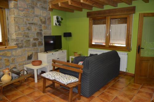 een woonkamer met een bank en een tv bij La Casa del Rio - La Lobera Casa Rural in Molinos de Razón