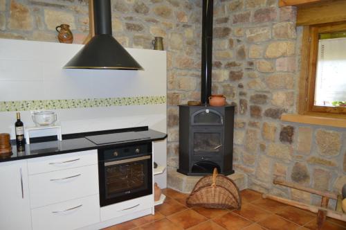Il comprend une cuisine avec une cuisinière et un mur en pierre. dans l'établissement La Casa del Rio - La Lobera Casa Rural, à Molinos de Razón