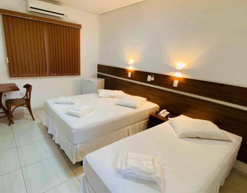 um quarto de hotel com duas camas e uma mesa em Hotel Garrafão - localizado no centro comercial de Boituva - SP em Boituva