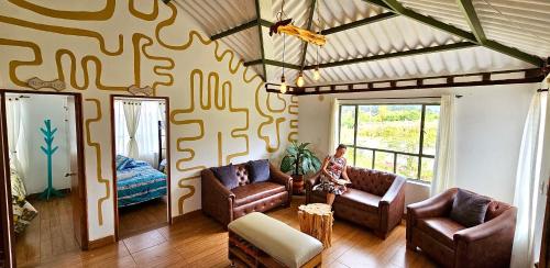 una sala de estar con dos sofás y una mujer sentada en un sofá en Madre Tierra- Casa hospedaje en Villa de Leyva