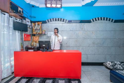 a man talking on a cell phone behind a red counter at OYO Royal Inn Near Iskcon Temple Bangalore in Bangalore