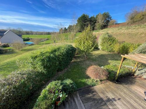 un jardin avec une terrasse en bois et un banc dans l'établissement Maison calme et cosy à Port-en-Bessin près du golf et de la mer, à Port-en-Bessin-Huppain