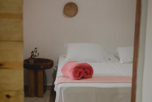 un animal de peluche rosa tirado en una cama en Casinhas da Serena - Casa cacau, en Caraíva
