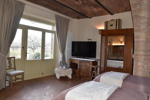 a bedroom with a bed and a flat screen tv at Agriturismo Poggio ai Legni in Sovicille