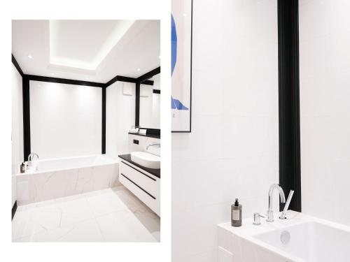 a white bathroom with a sink and a bath tub at Suite Sixteen Szafarnia in Gdańsk