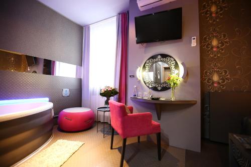 a hotel room with a pink chair and a mirror at Hotel Forma in Piła