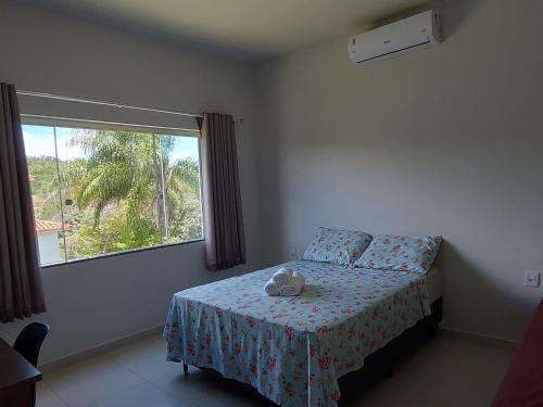 a bedroom with a bed with a stuffed animal on it at Suítes Canaã in Capitólio