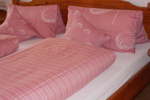 a bed with pink and white sheets and pillows at Gaestehaus Hofer in Bad Birnbach