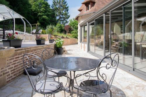 a glass table and chairs on a patio at Le prieuré des fontaines in Les Préaux