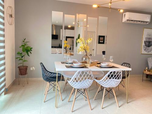 une salle à manger avec une table et des chaises blanches dans l'établissement Casa Mazatlán, alberca, baño y clima en cada habitacion, à Mazatlán