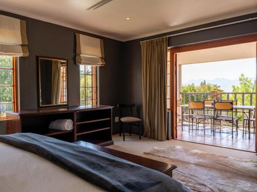 a bedroom with a bed and a balcony with a table and chairs at Serenity Lodge in Clarens