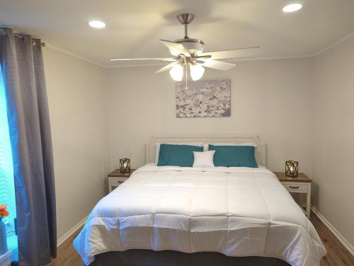 a bedroom with a white bed with a ceiling fan at The Comfort Zone in Baton Rouge