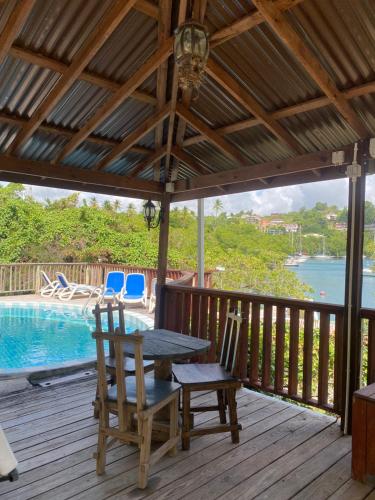 eine Terrasse mit einem Tisch, Stühlen und einem Pool in der Unterkunft Blue Bamboo cottage Marigot Bay. in Marigot-Bucht