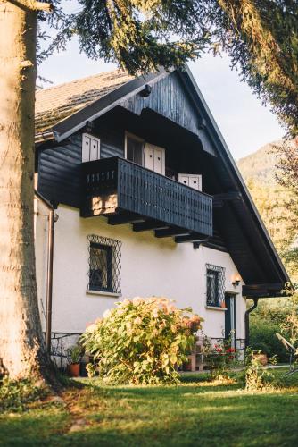 a white house with a balcony and a tree at River house HRIB in Preddvor