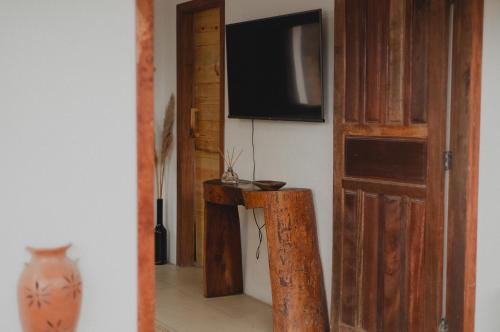 a room with a television and a table with a vase at Casinhas da Serena - Casa concha in Caraíva