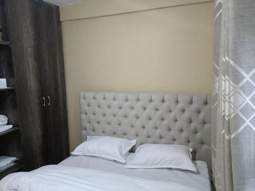 ein Schlafzimmer mit einem großen Bett mit weißer Bettwäsche und Kissen in der Unterkunft D.S Apartment in Kakamega
