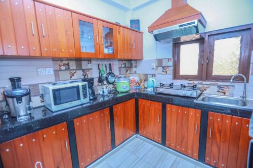 パナドゥラにあるSilverin Rest Apartmentのキッチン(木製キャビネット、電子レンジ付)