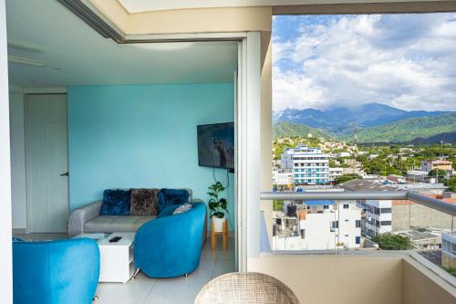 a living room with blue chairs and a large window at Apartamento - Velas al Mar, Santa Marta in Gaira
