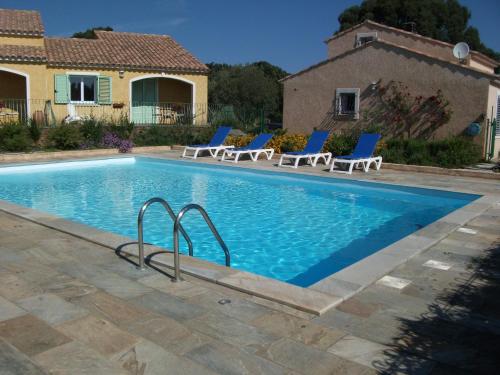 a swimming pool with chairs and a house at Gîtes Santa Maria Cap Corse in Macinaggio