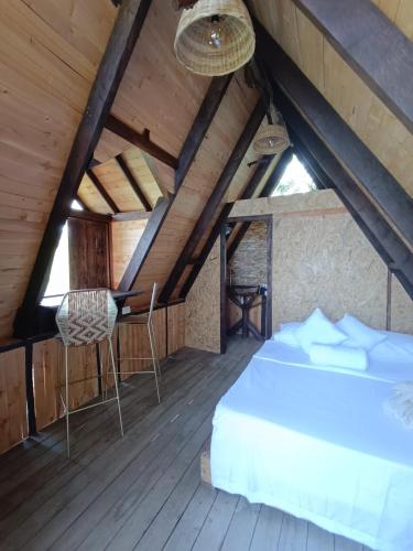 1 dormitorio con 1 cama y sillas en un ático en Glamping el nido, en Curití