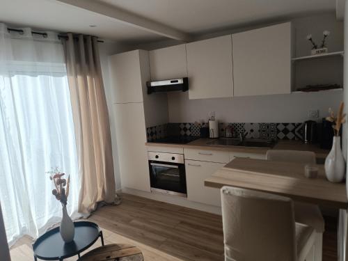 a kitchen with white cabinets and a table with a vase at La pause bretonne in Quéven