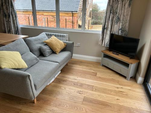 a living room with a couch and a flat screen tv at The Cabin at the Croft - Idyllic rural retreat perfect for couples and dogs in Leigh