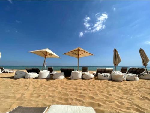a row of chairs and umbrellas on a beach at Sand Castle Villa Azha - 2 bedrooms - Next Tanoak Hotel in Ain Sokhna