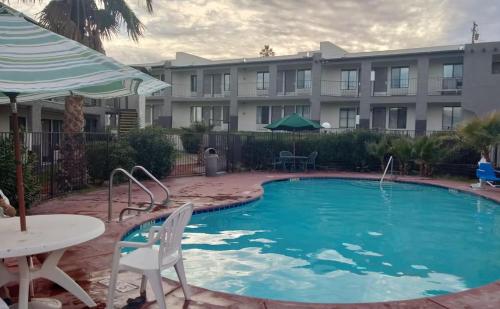 une piscine avec une table et des chaises et un bâtiment dans l'établissement Super 8 by Wyndham Barstow, à Barstow