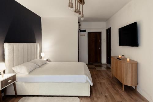 a bedroom with a white bed and a television at Blue Harmony Apartment in Floreşti