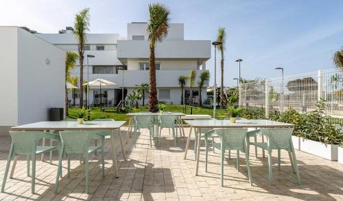 eine Terrasse mit Tischen und Stühlen und ein Gebäude in der Unterkunft Ático Ceitil Candor in Rota