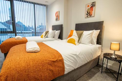 two beds in a bedroom with a large window at Luxury City Centre Apartment (Weekly Booking) in Hull