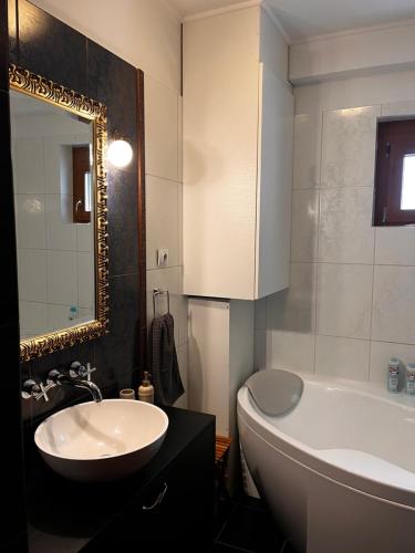 y baño con lavabo, bañera y espejo. en Bárány Apartman en Pécs