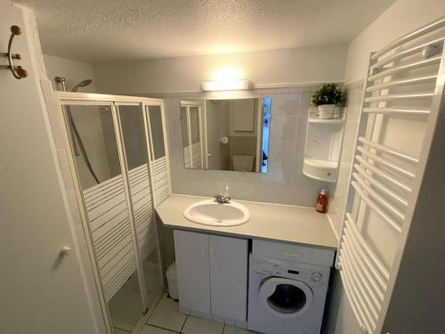 une salle de bain avec un lavabo et une machine à laver dans l'établissement Aurora Surf Lodge maison Mer, à Saint-Vincent-sur-Jard