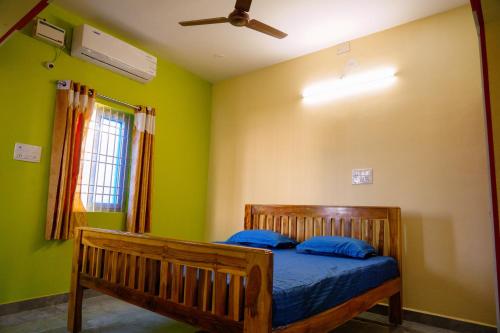 1 dormitorio con cama de madera y almohadas azules en Sri Sakthi Residence en Tiruvannāmalai