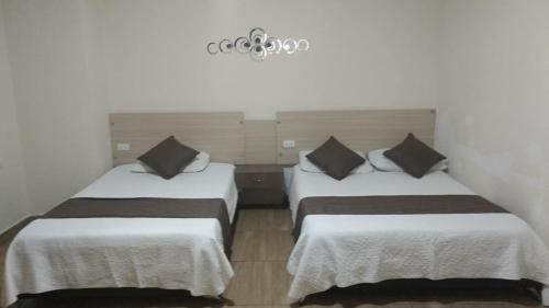 two beds in a room with white sheets and black pillows at HOTEL STERLING in Cúcuta