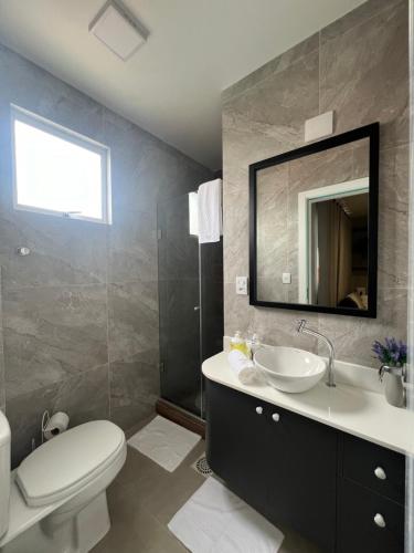 ein Badezimmer mit einem Waschbecken, einem WC und einem Spiegel in der Unterkunft Apartamento em Sapucaia do Sul in Sapucaia