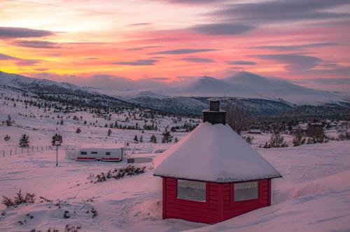 a red building in the snow with a mountain in the background at Rondane Haukliseter Fjellhotell in Høvringen