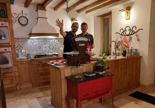 two men standing in a kitchen with their hand in the air at Aux Sources de Ouanne in Ouanne