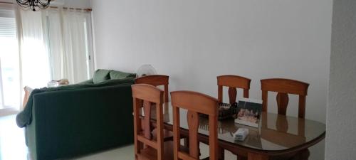 a dining room table and chairs and a green couch at El mirador de la Ría in Isla Cristina